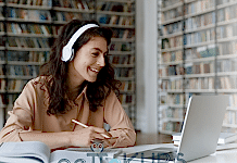 Kısa Sürede DGS’ye Nasıl Hazırlanılır? Kulaklıkla online ders izleyen genç kadın, kütüphane ortamında bilgisayarla ders çalışıyor.